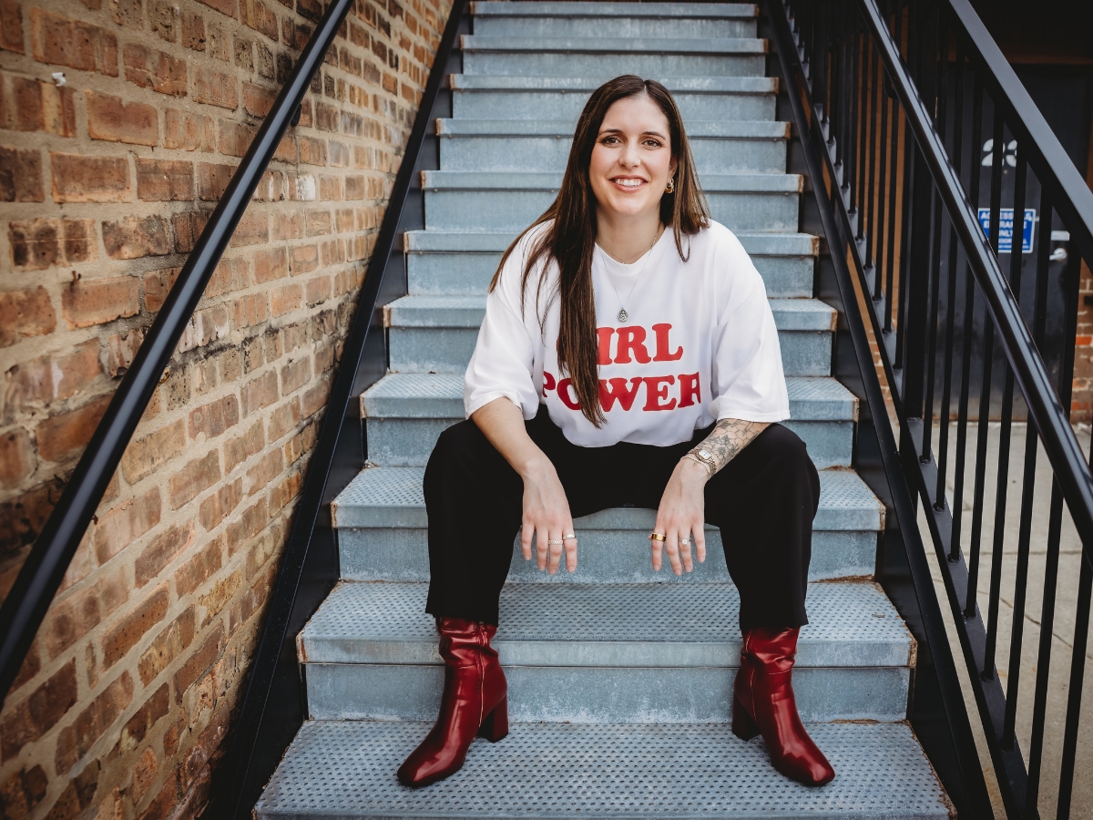Small business social media manager sitting on stairs smiling confidently